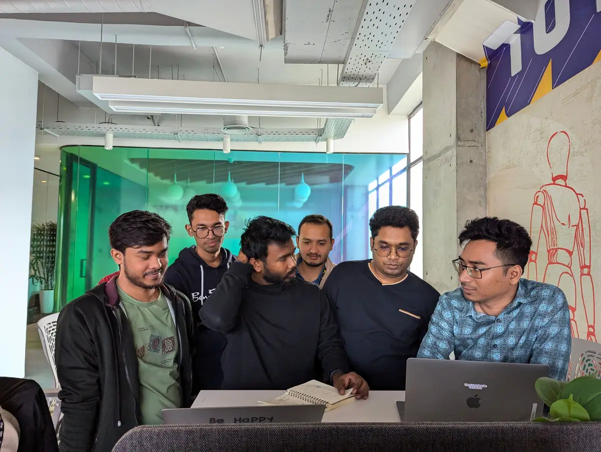 An agency team gathered around a laptop reviewing work